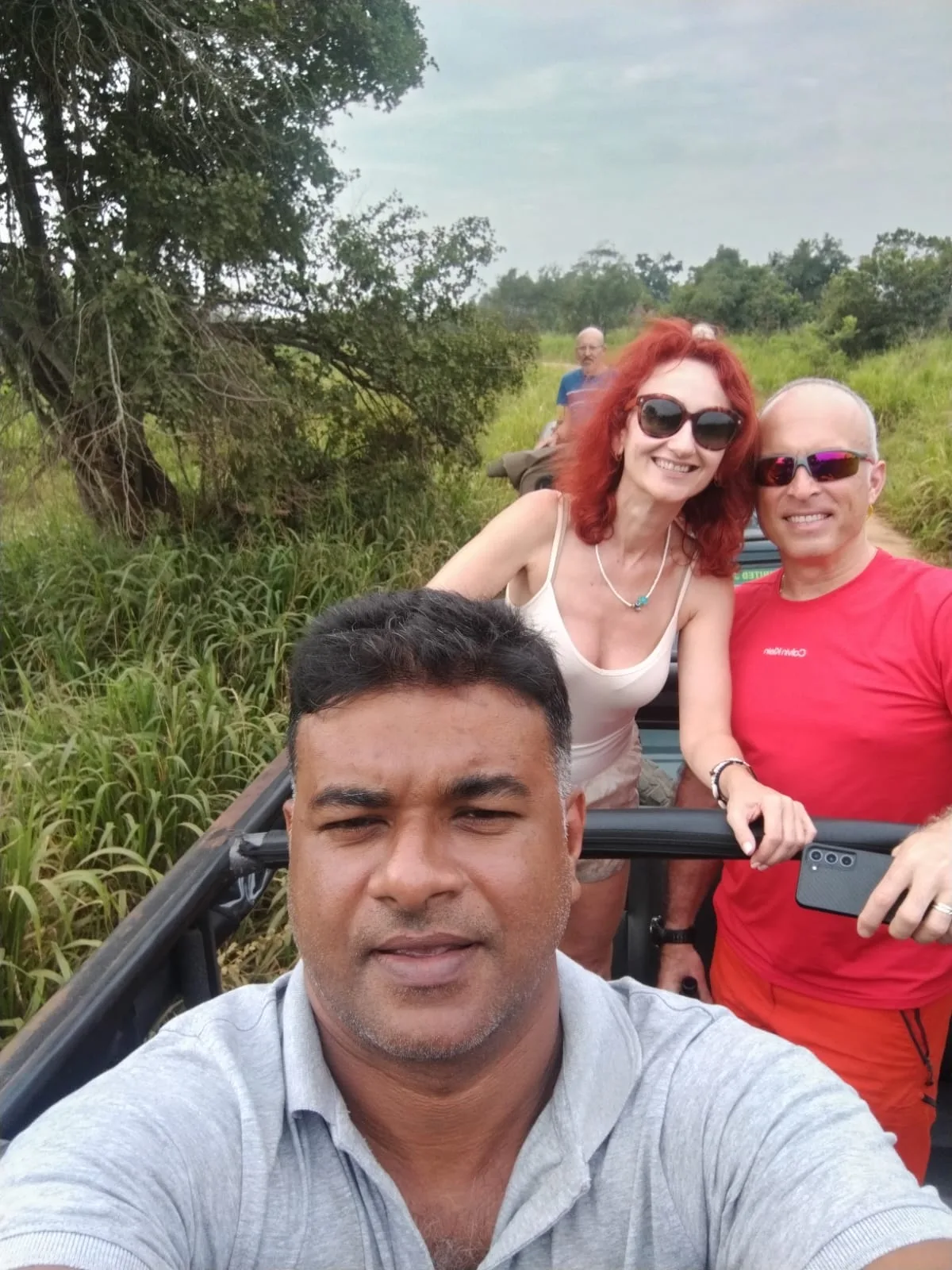 A Sammy Tours guide taking a cheerful group selfie with guests from an open safari vehicle