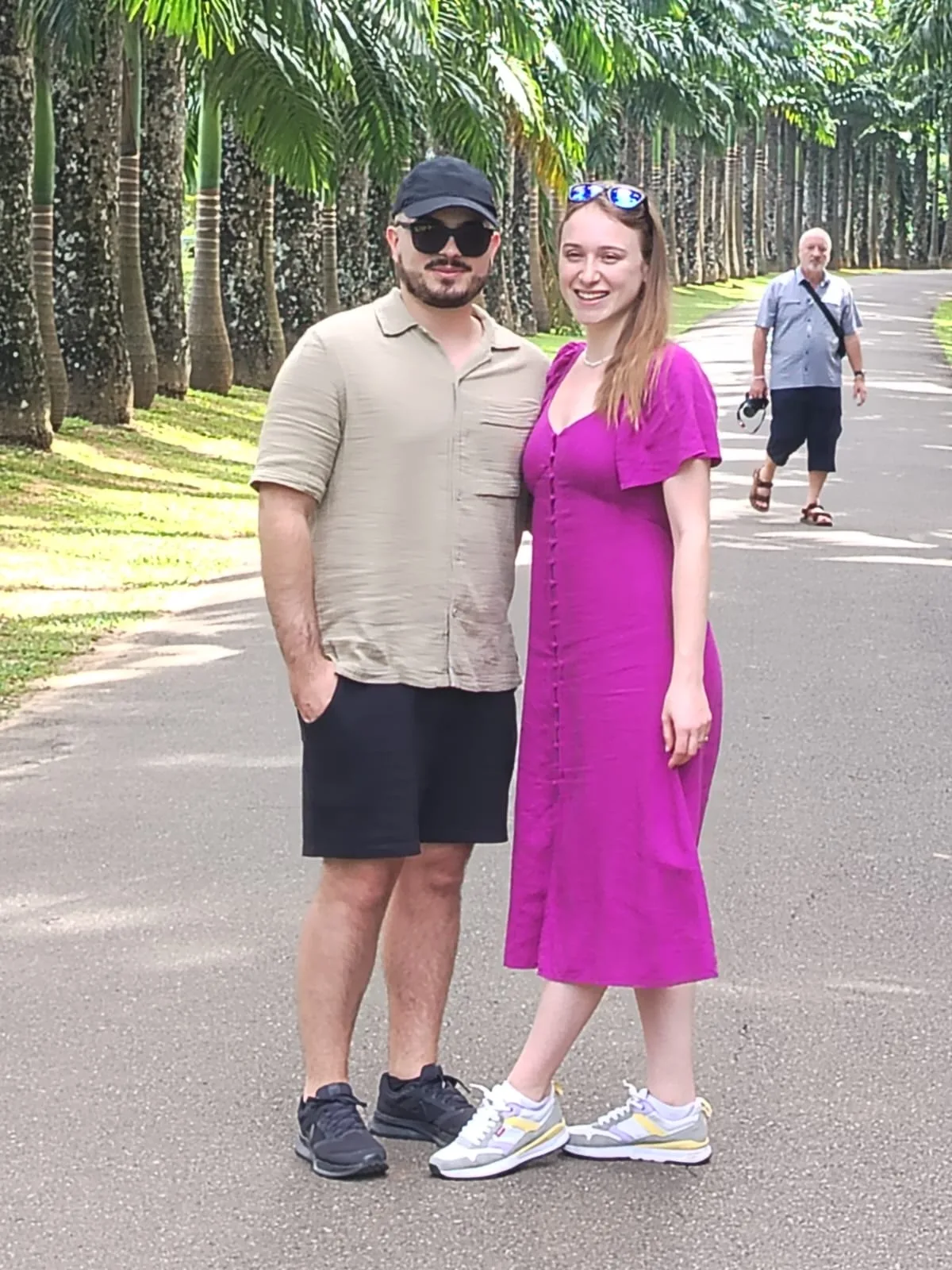 A couple smiling together on a broad Sri Lankan avenue bordered by rows of royal palms