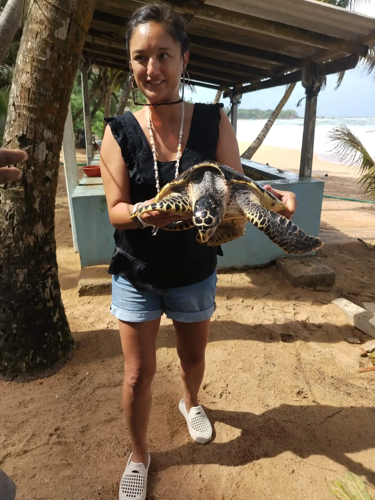 A smiling river safari guest with a young crocodile resting carefully across his shoulder