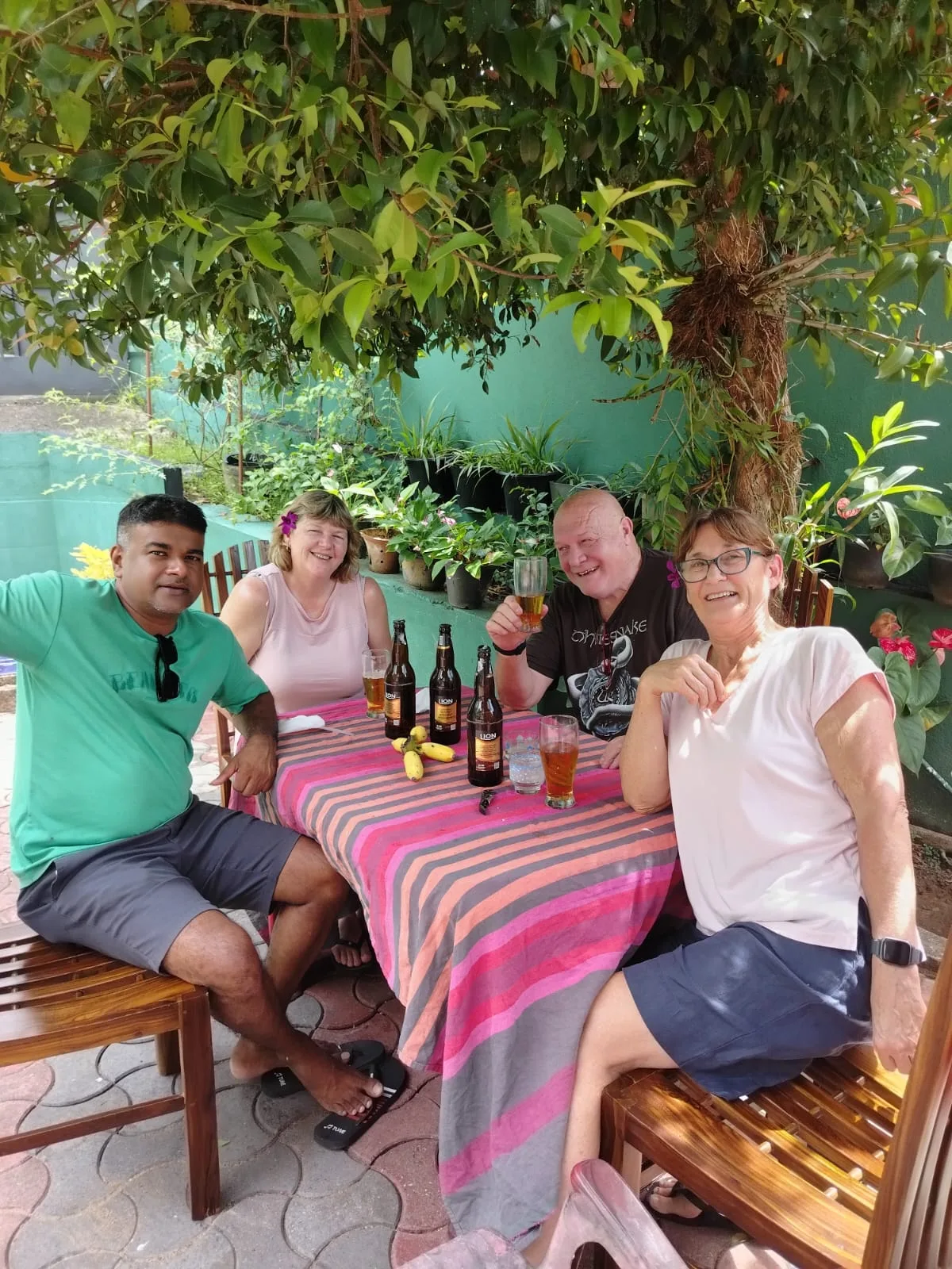 A Sammy Tours guide and three guests sharing drinks together around a shaded outdoor table
