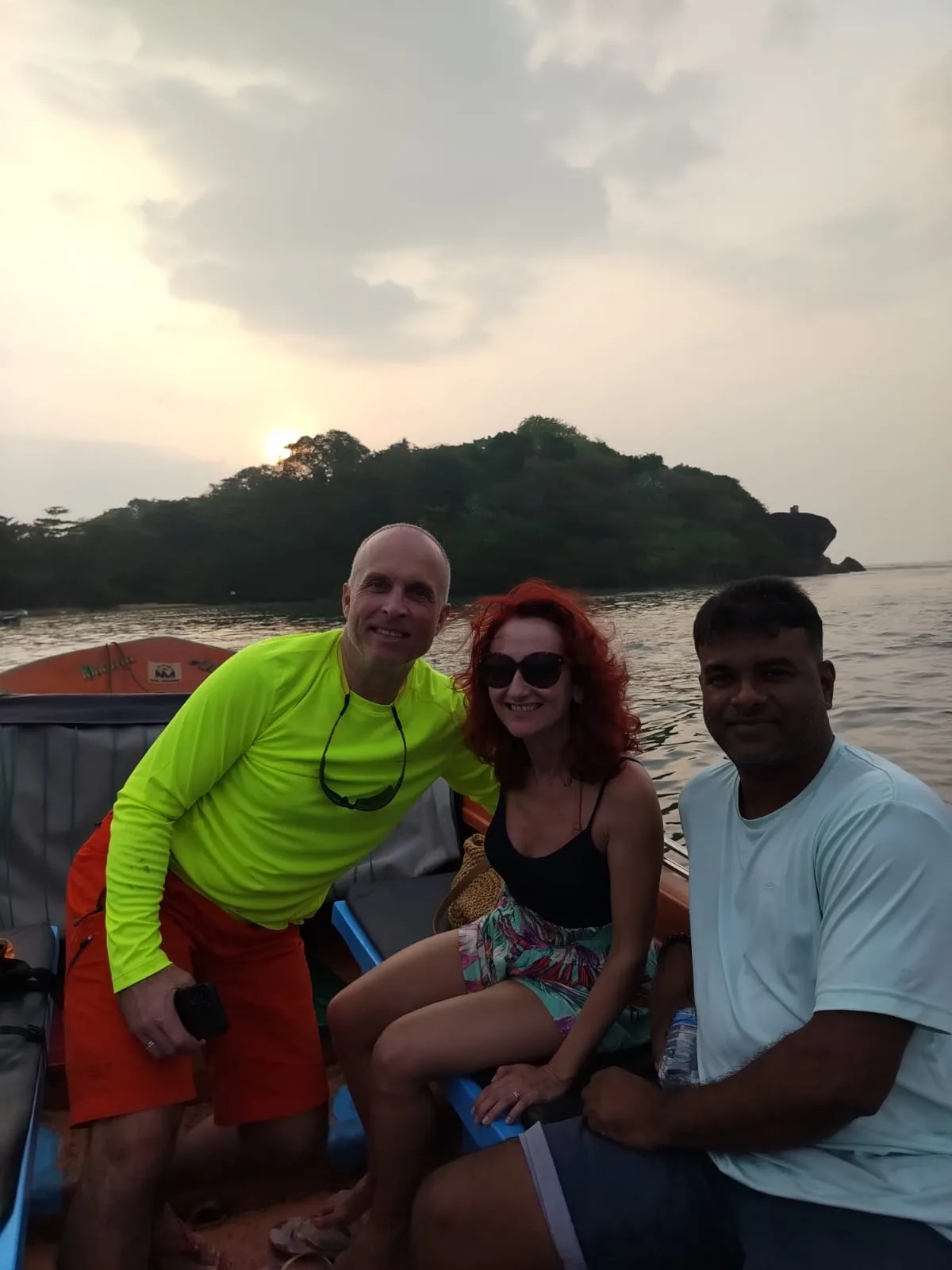 Two guests and their Sammy Tours guide smiling aboard a boat near the southern coast at sunset