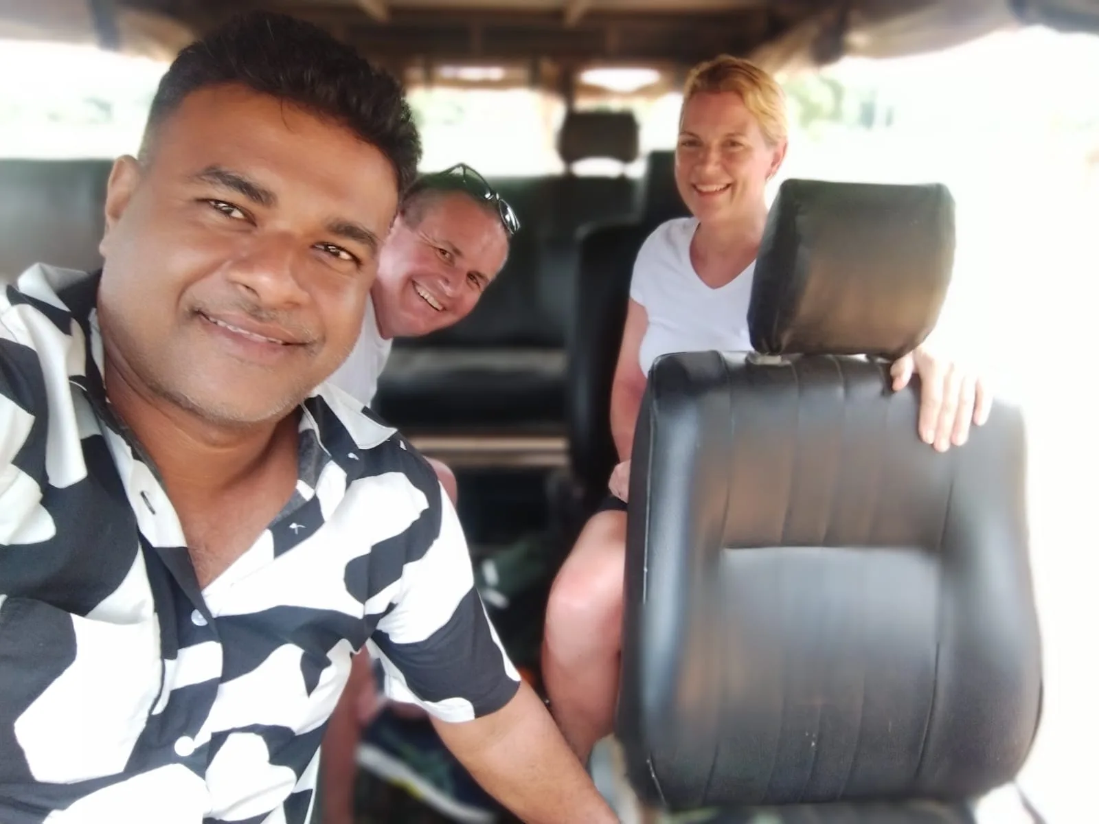A Sammy Tours guide and two guests smiling together inside their private tour vehicle