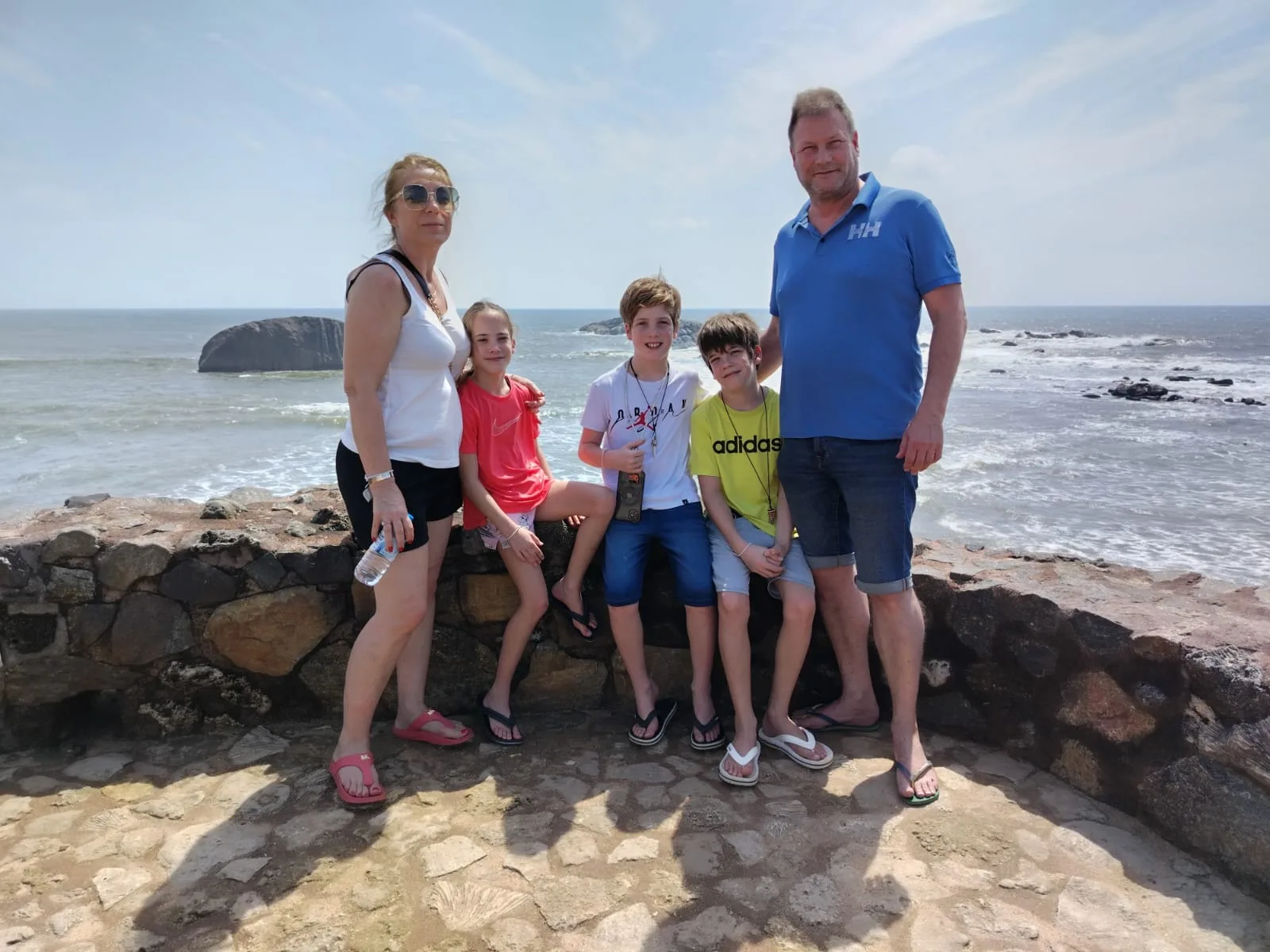 A family posing together above the ocean on Sri Lanka's sunny southern coast