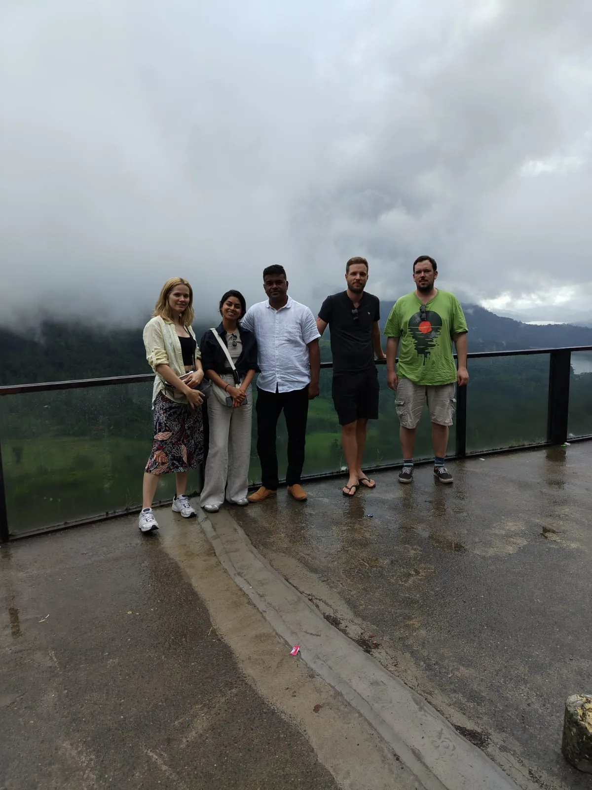 A Sammy Tours guide and four guests standing together at a misty viewpoint in Sri Lanka's hill country