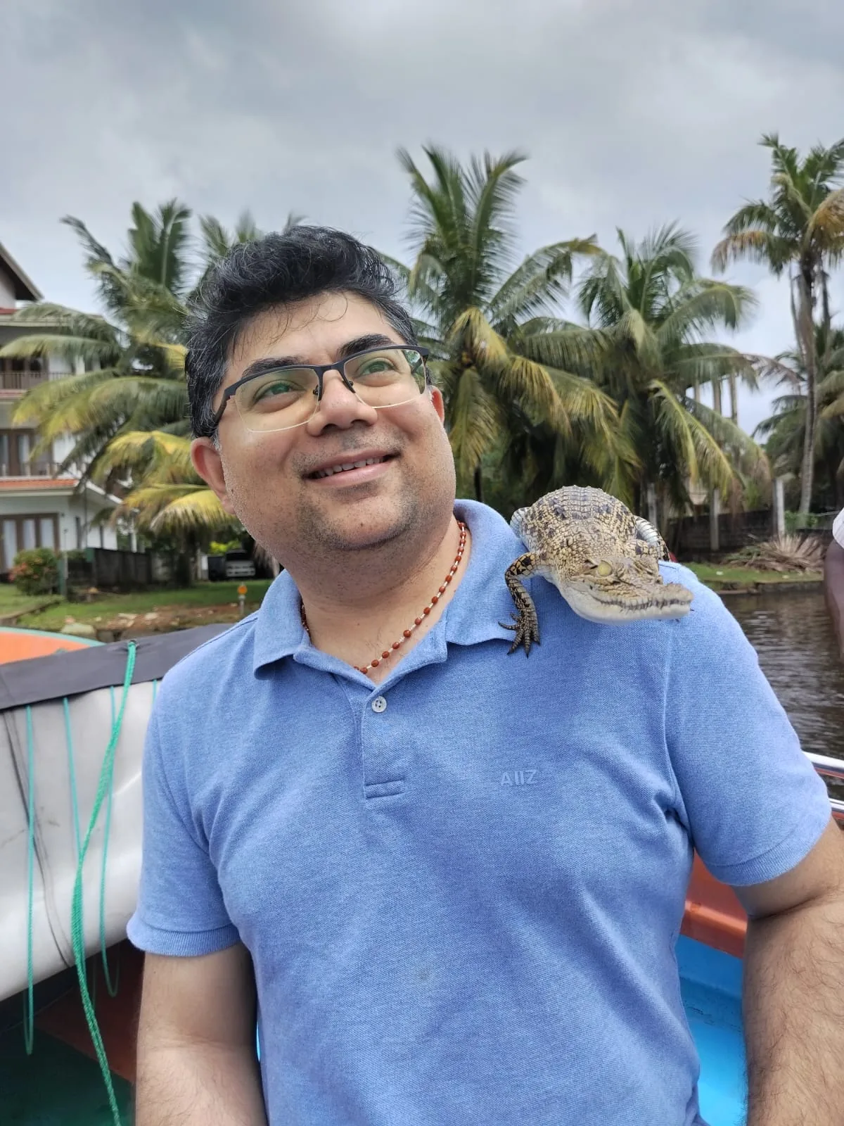 A river safari guest smiling as a young crocodile rests carefully on his shoulder